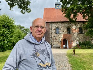 Pastor i.R. Rolf Fröhlich vor der Hittfelder Mauritiuskirche. Foto: C.Wöhling